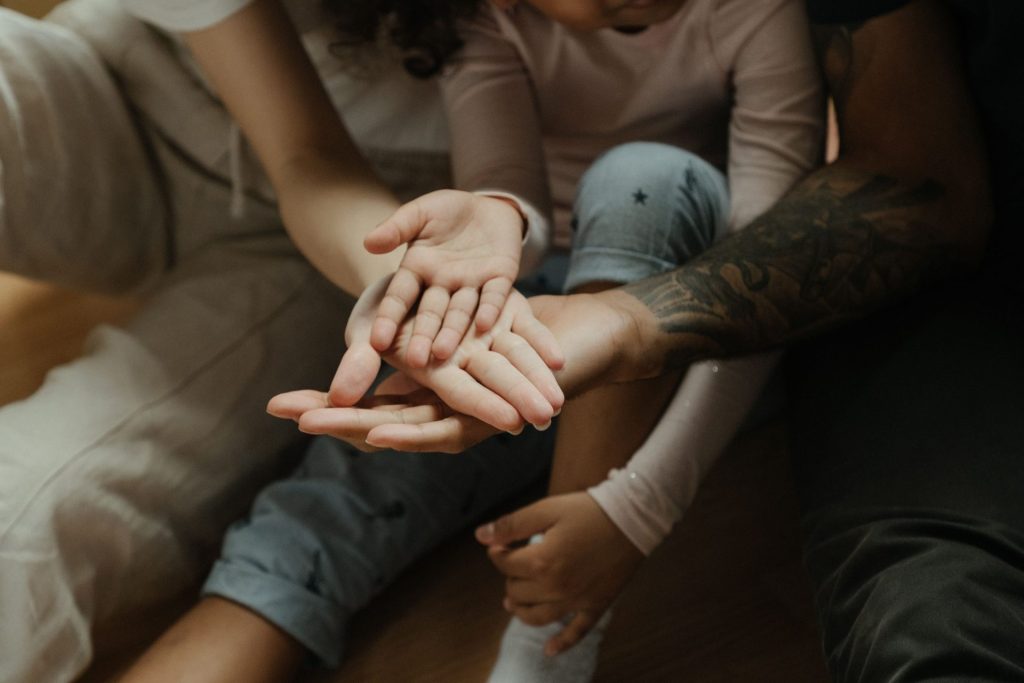 Gros plan sur des mains de membres d'une même famille, symbolisant les liens et la chaleur humaine.